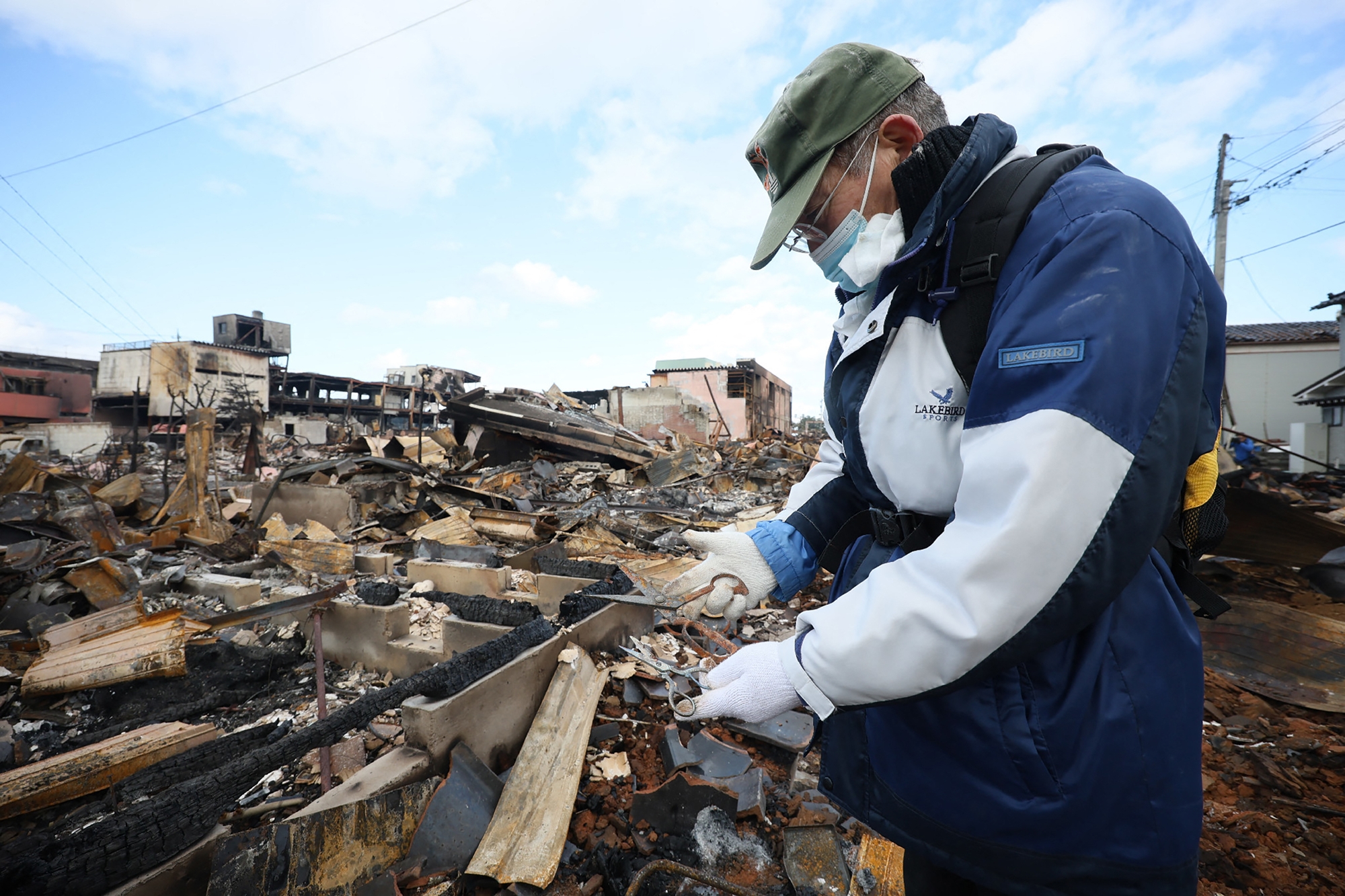 Người đàn ông tìm kéo cắt may của vợ trong ngôi nhà bị hỏa hoạn phá hủy ở thành phố Wajima, tỉnh Ishikawa, ngày 4/1. Ảnh: AFP